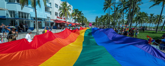 People with large rainbow flag on Miami Beach | LGBTQ+ rights are human rights