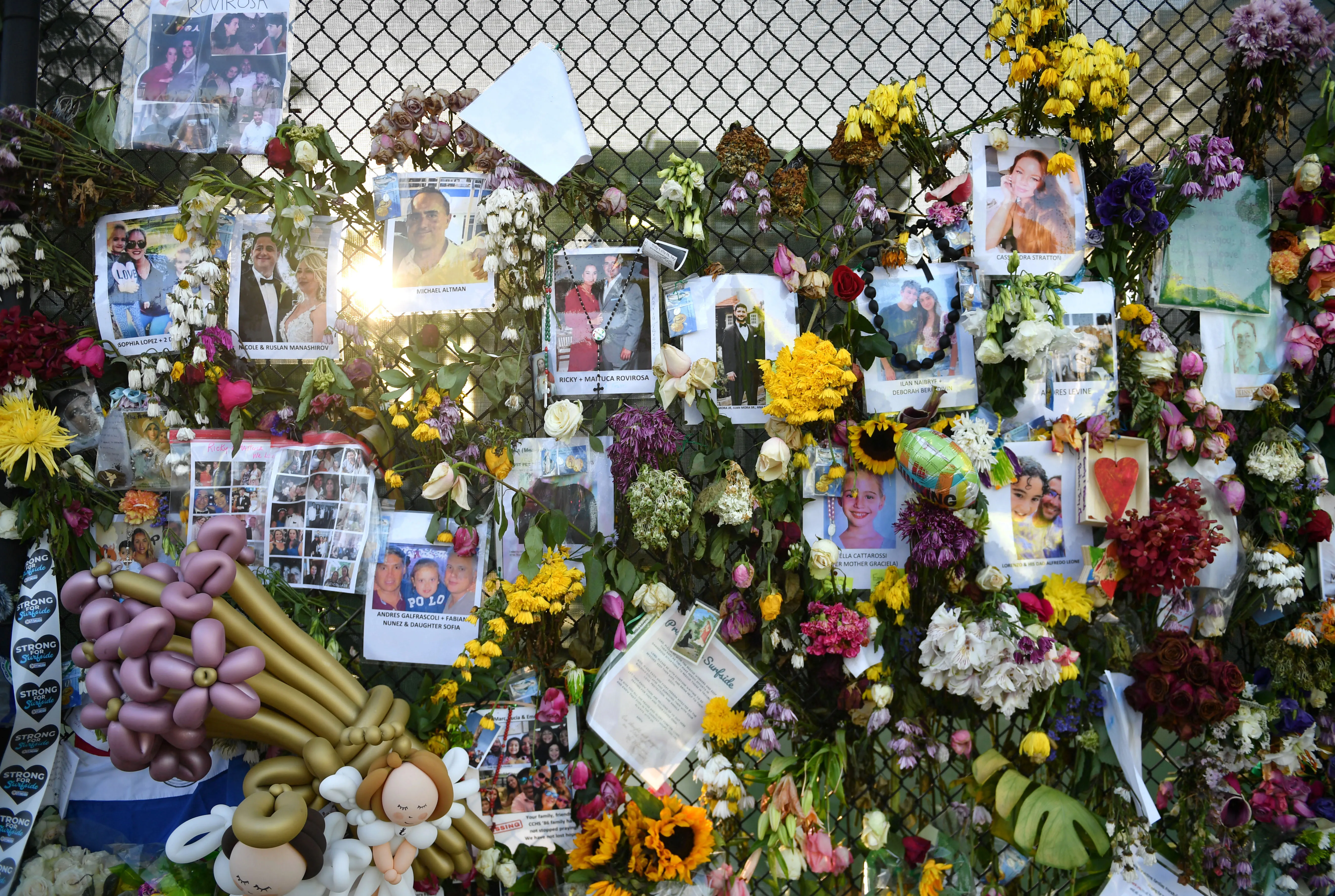 Photo of the Surfside Wall of Hope and Memorial featuring photos of the collapse victims, flowers, and cards.